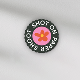 Shot on paper shoot text lens cover with centre red and yellow flower graphic with grip groves 